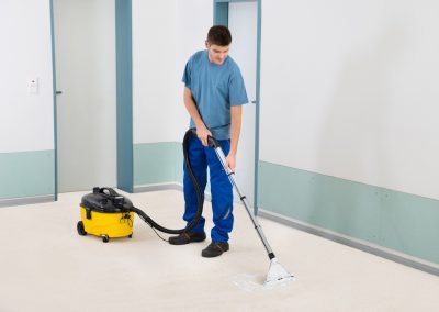 Male Cleaner Vacuuming Floor