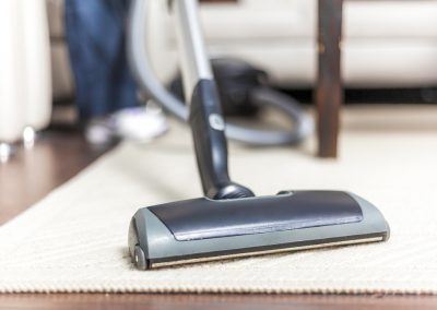 A woman vacuuming her white carpet